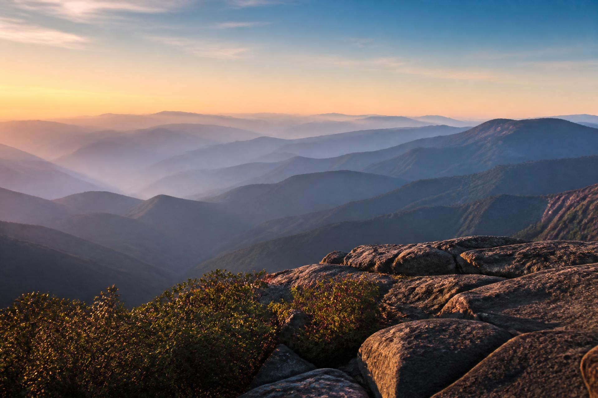 View from a mountaintop looking across layered ridges into the distance